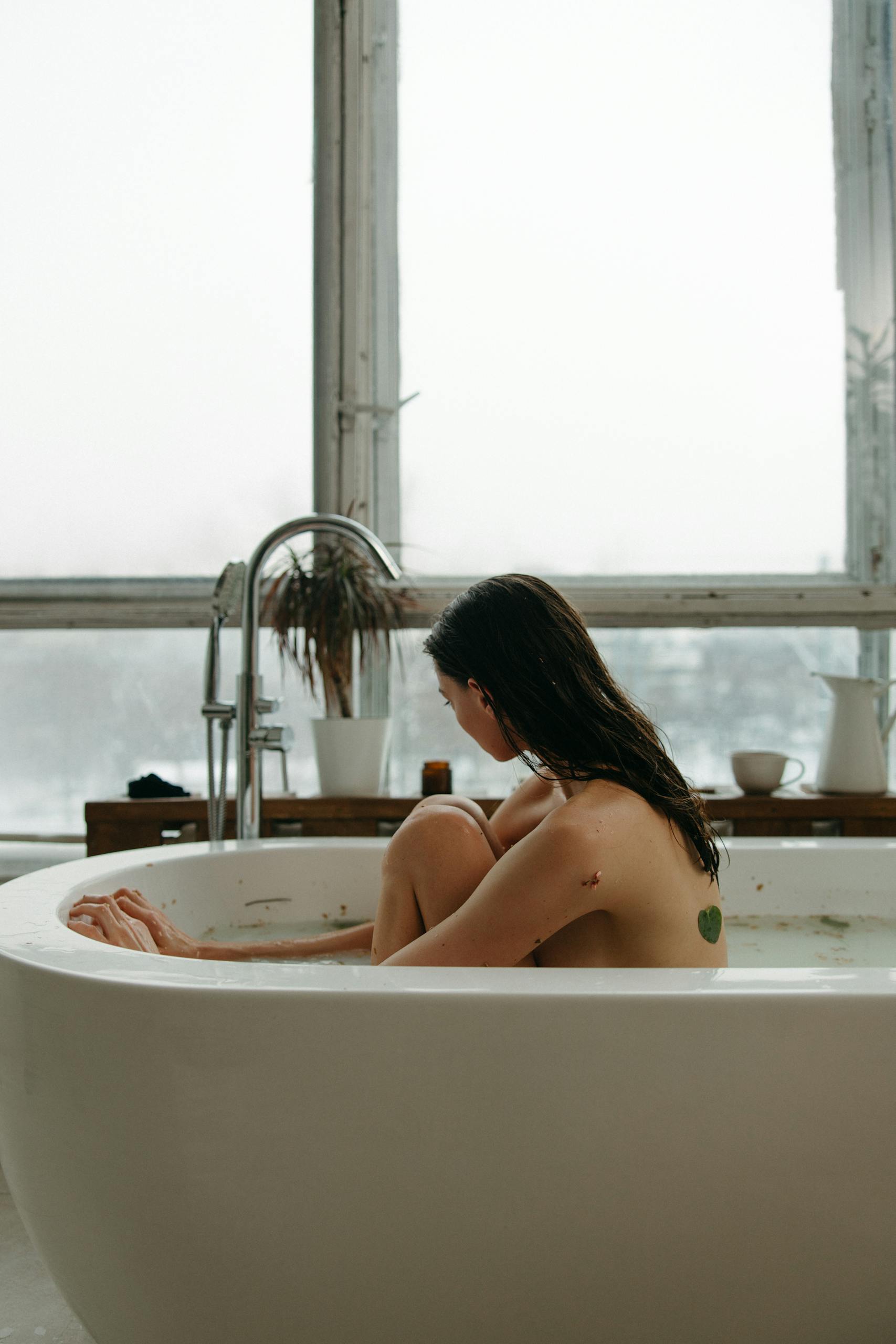A young woman enjoying a relaxing bath indoors, embracing self-care and tranquility.