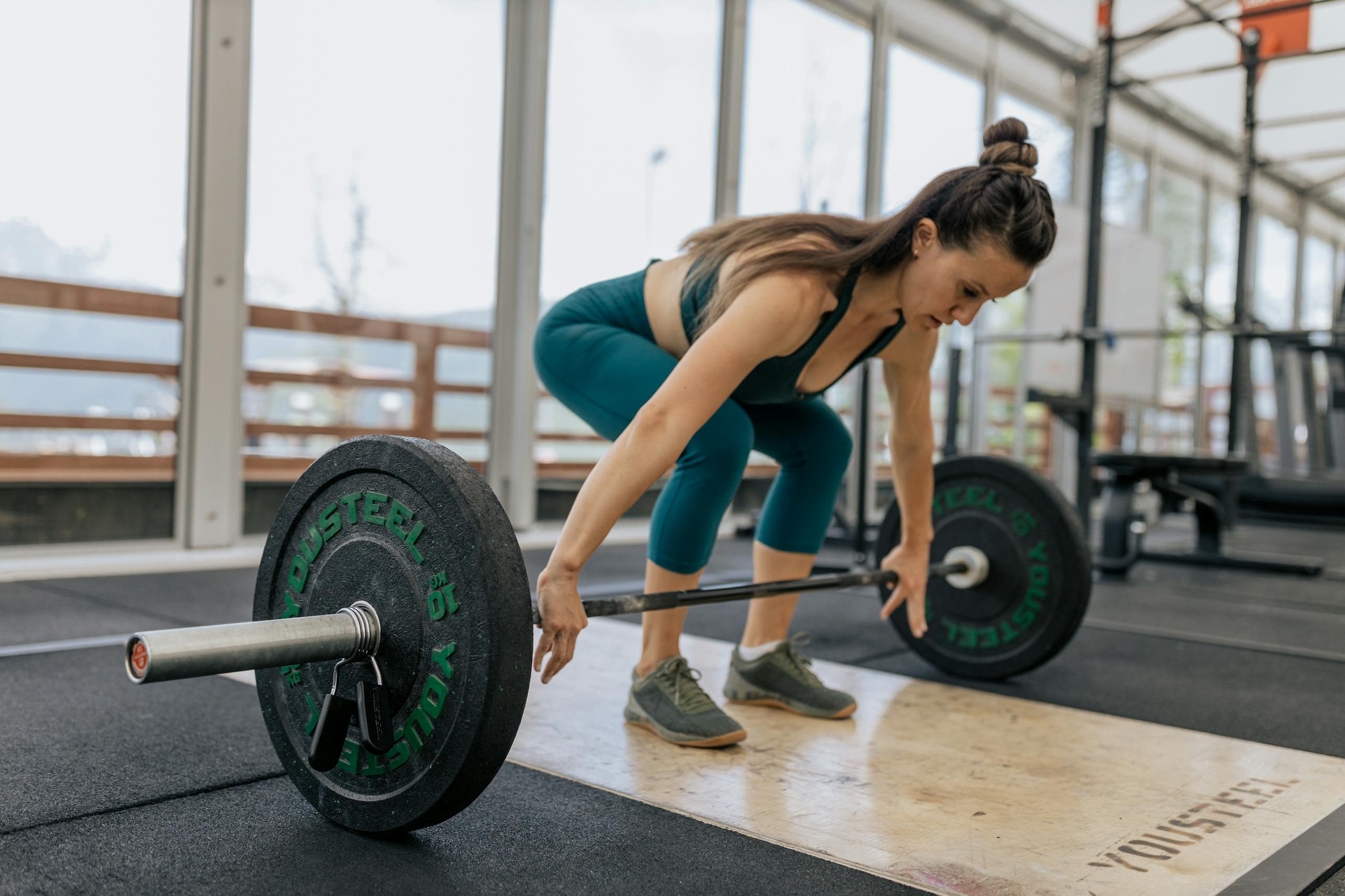 Home 57 Focused woman lifting barbell in gym, showcasing strength and fitness.